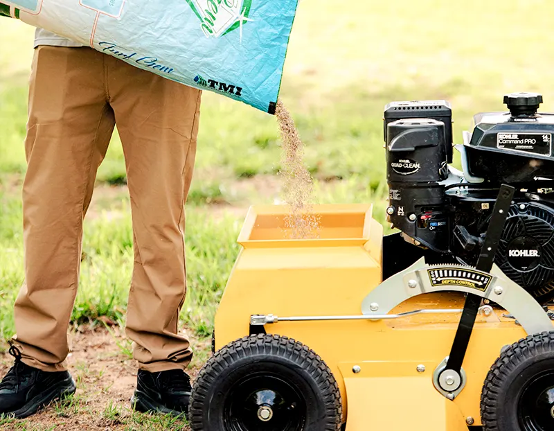 Closeup of loading power seeder with fescue seed