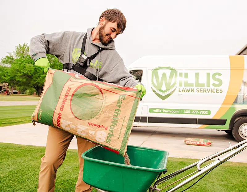Willis Lawn Service tech smiling while adding Earthworks Replenish Soil Conditioner to spreader